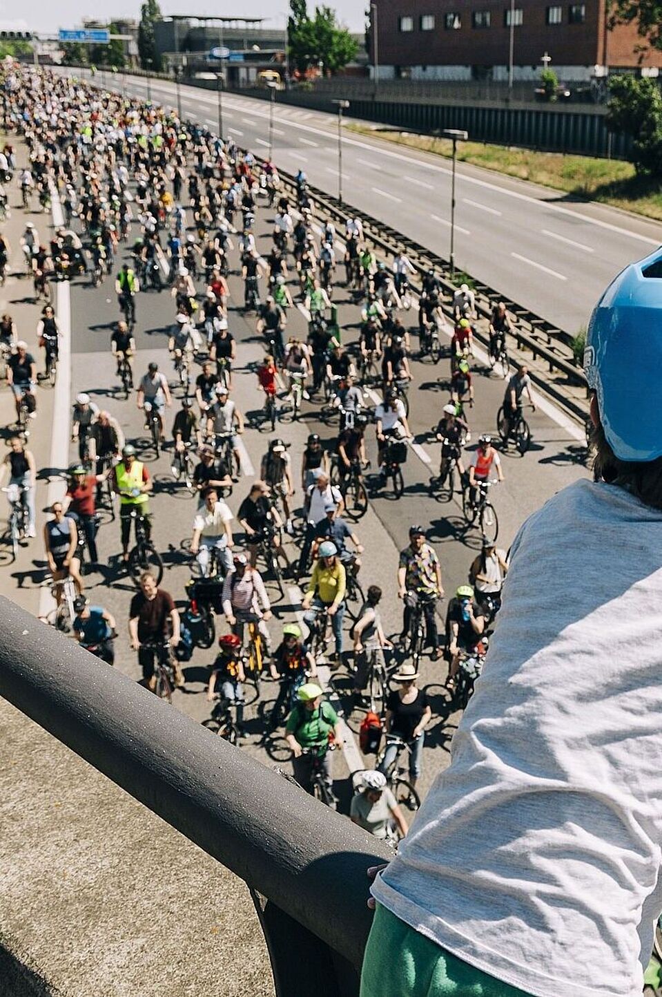 ADFC-Sternfahrt Kind mit blauem Helm guckt auf Autobahn über die auf einer Seite hunderte FahrradfahrerInnen fahren